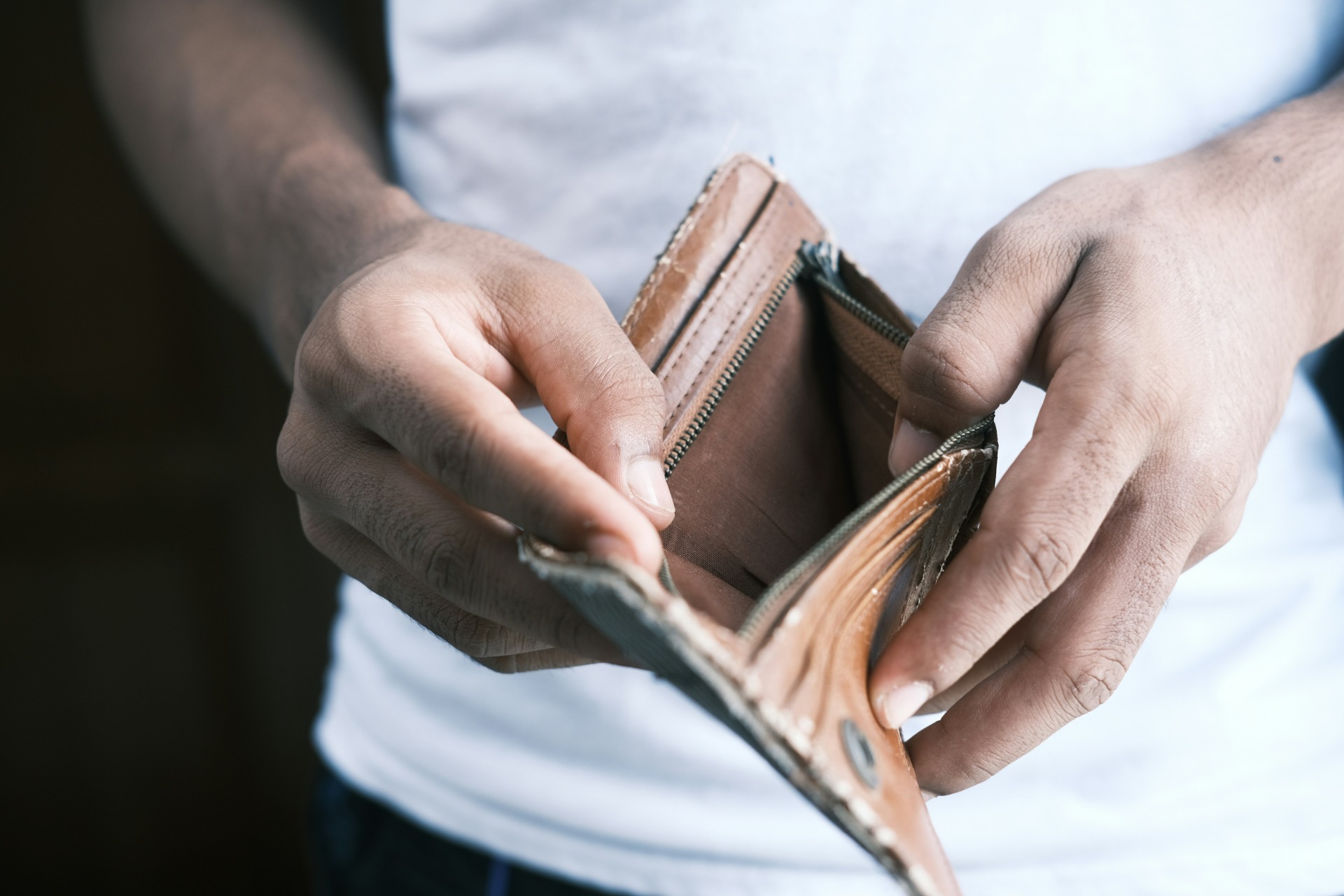 credito - Mãos segurando uma carteira de couro aberta, mostrando o interior vazio, em close.